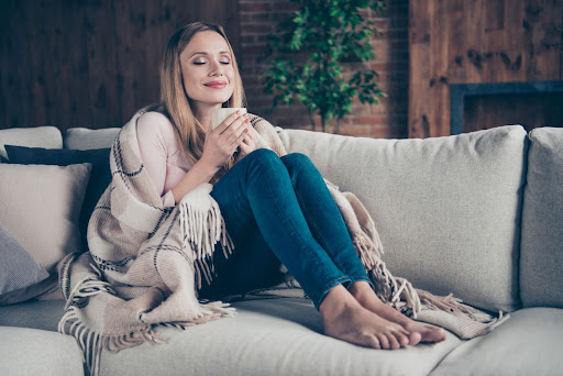 Femme sur un canapé, au chaud en intérieur 